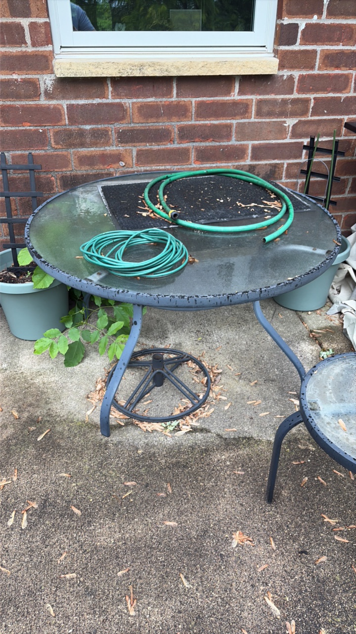 Two outdoor glass tabletop tables, one side table, one full table, and umbrella stand.