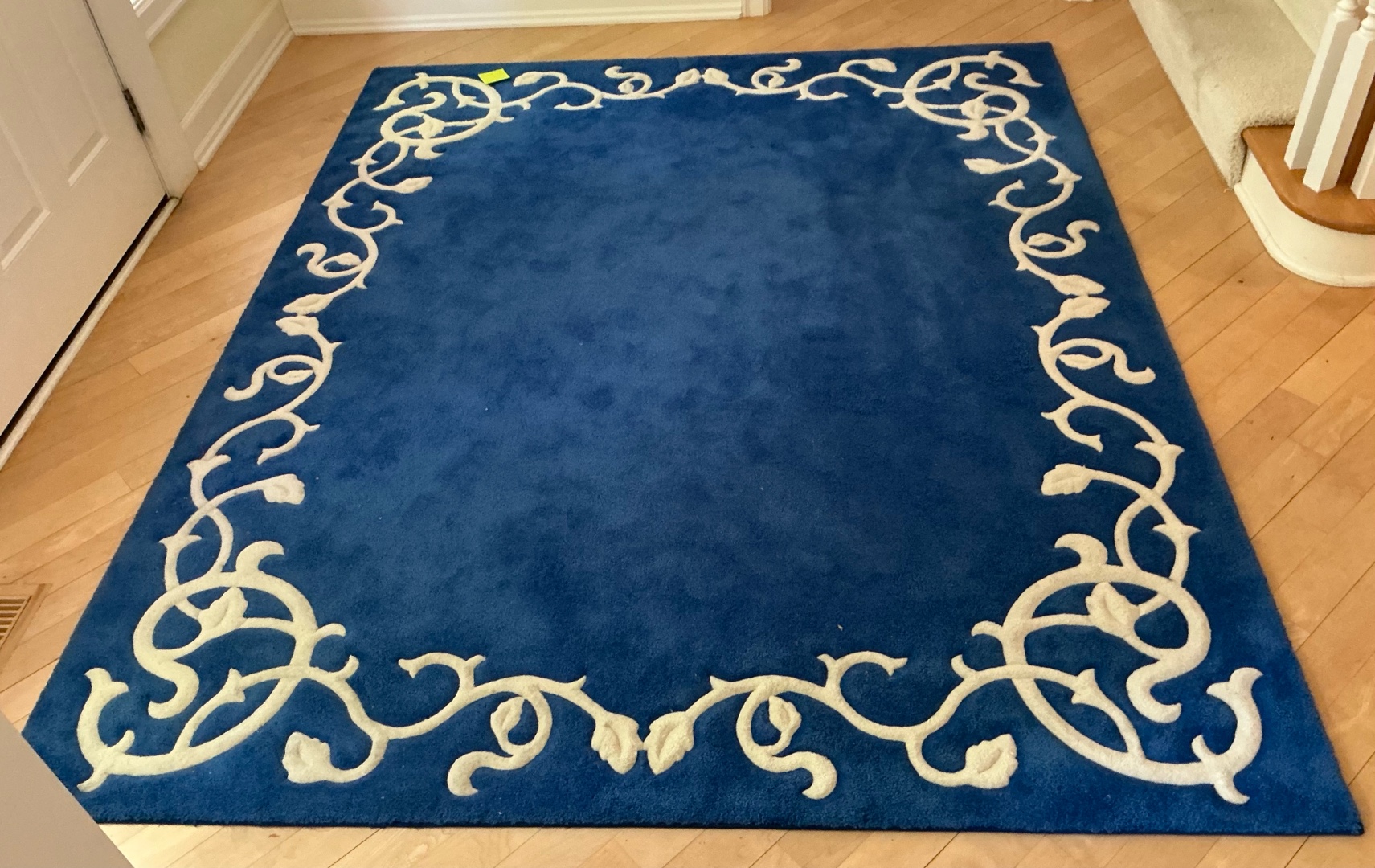 Blue area rug with distinctive cream-colored floral border pattern